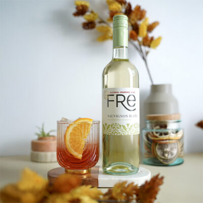 color image of a bottle of FRE Alcohol-Removed Sauvignon Blanc with an orange cocktail with an orange slice as a garnish