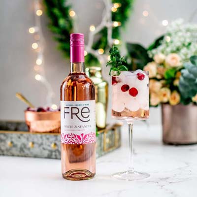 color image of a bottle of FRE Alcohol-Removed White Zinfandel next to a pink mocktail with ice and berry garnishes