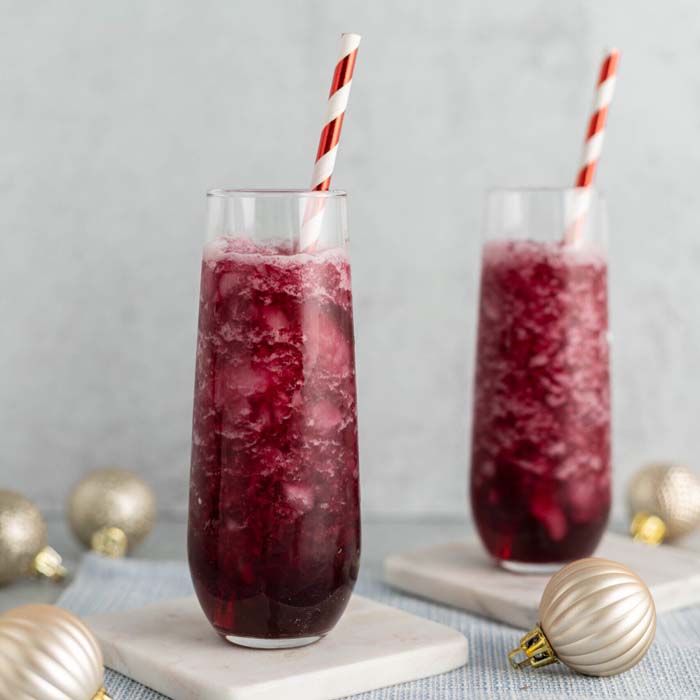 color image of 2 deep red mocktails in stemless flute with red and white striped straws