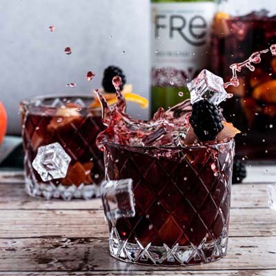 color image a purple cocktails with blackberry garnishes and a bottle of FRE Alcohol-Removed Red Blend