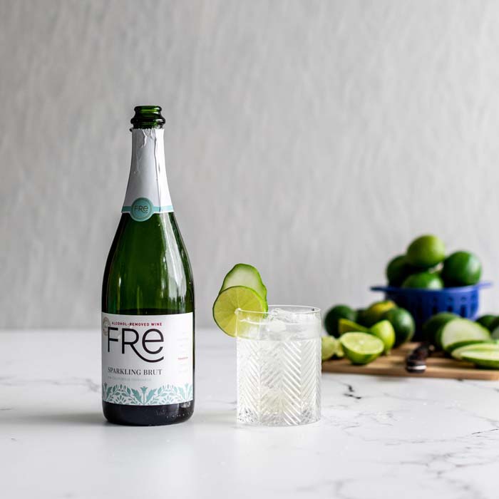 color photo of a bottle of FRE Alcohol-Removed Sparkling Brut next to a clear cocktail with lime garnishes