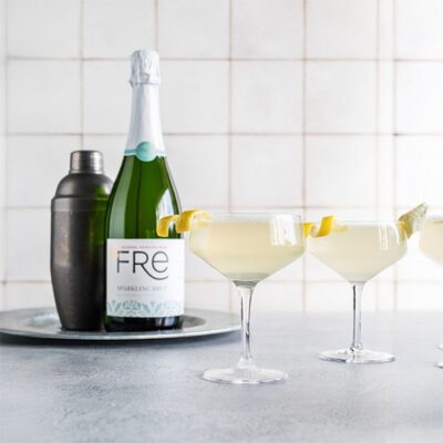 color image of a bottle of FRE Alcohol-Removed Sparkling Brut with 2 cocktails with a lemon twist as a garnish