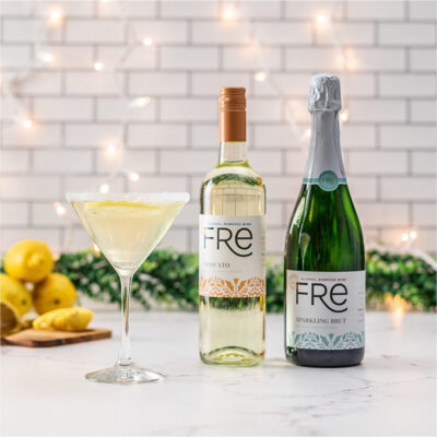 color image a bottle of FRE Alcohol-Removed Moscato and FRE Alcohol-Removed Sparkling Brut next to a mocktail on a white counter