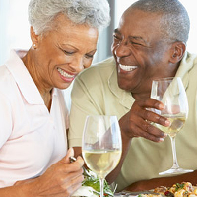 Mature couple laughing together holding wine glasses filled with white wine