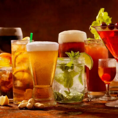 Colorful arrangement of various drinks including beer, wine, and cocktails, in a variety of different glasses