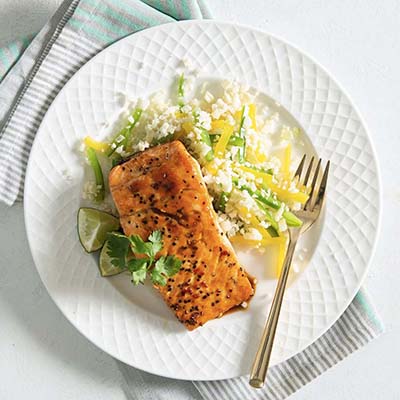 Bird's eye view of a plate with salmon, lime wedges, and a side salad